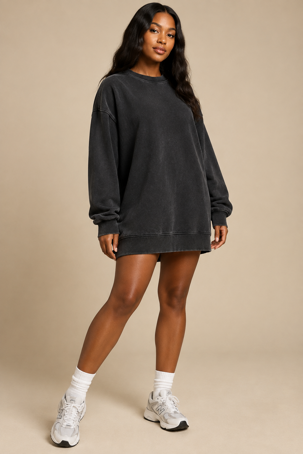 Black female model wearing a black vintage-wash oversized cotton sweatshirt dress in a studio setting
